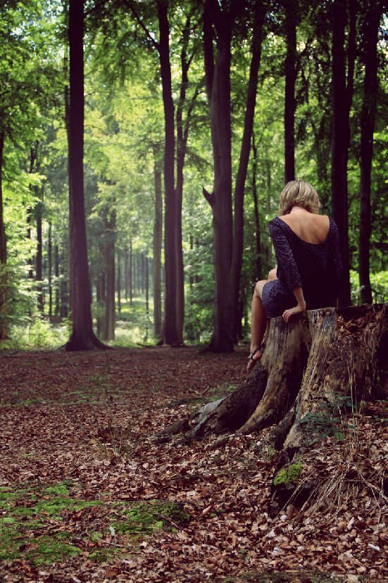 Femme assise sur une souche en forêt